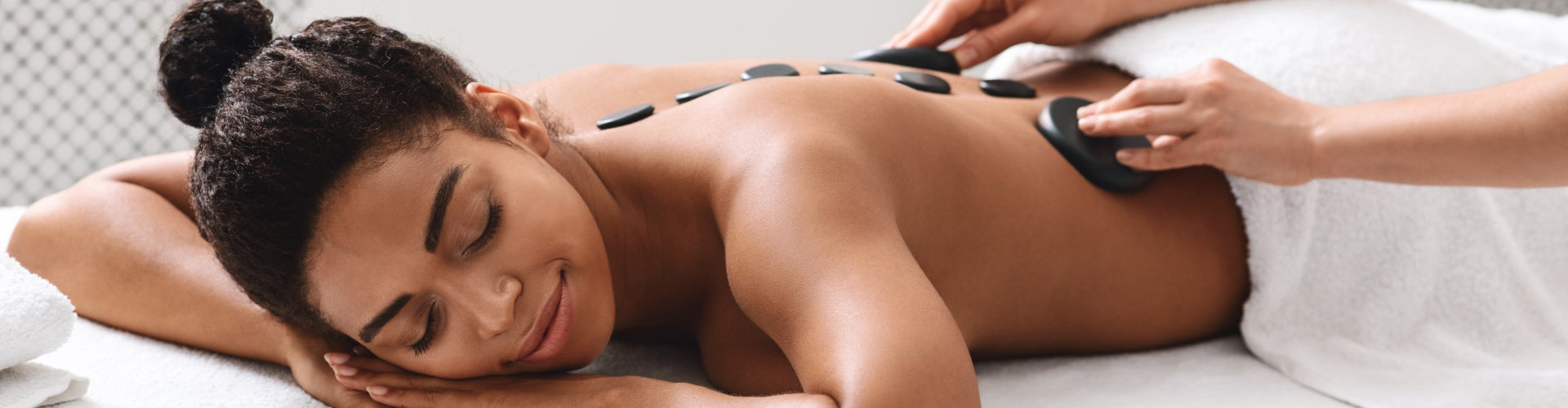 therapist placing hot stones on black girl back